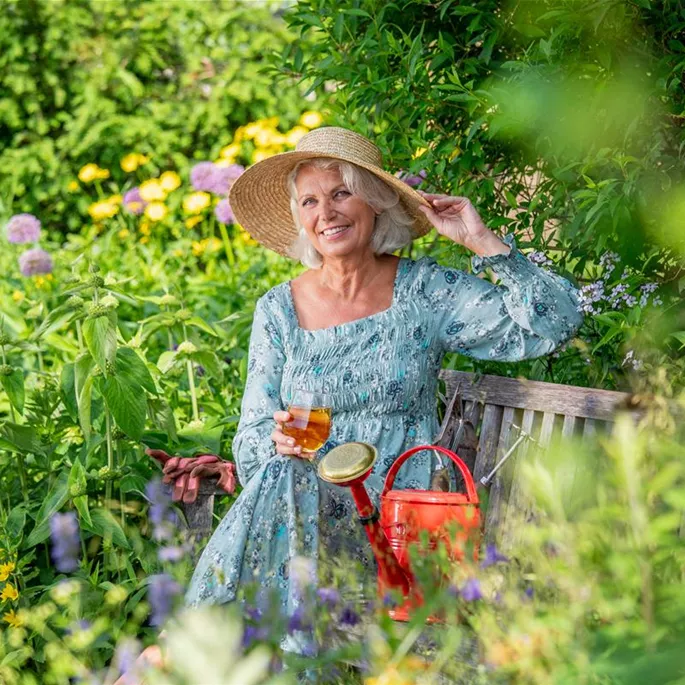 Gartenfreizeit - Frau sitzt auf Gartenbank